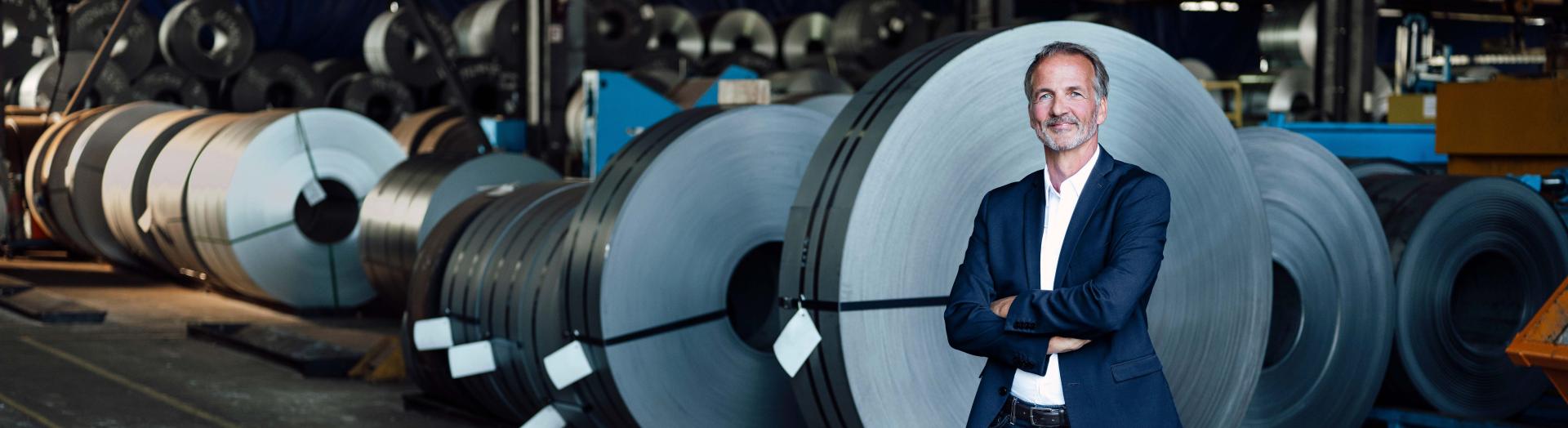 Business Man in Lagerhalle mit Kabeltrommeln