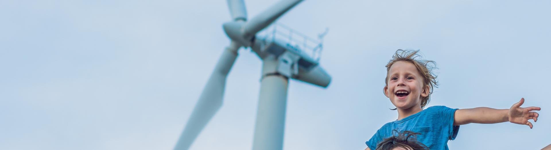 Mann mit Kind auf den Schultern und ein Windrad im Hintergrund