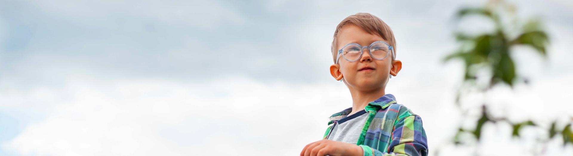 Kleiner Bub mit Brille auf einer Leiter in einem Kirschbaum