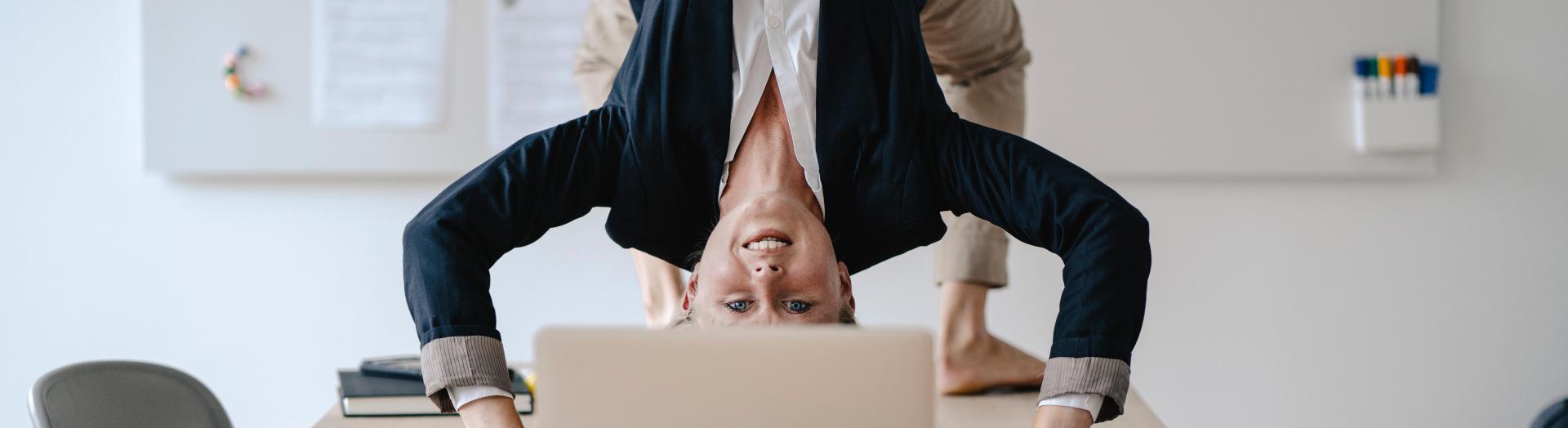 Businesslady im Anzug macht Yoga-Brücke am Tisch