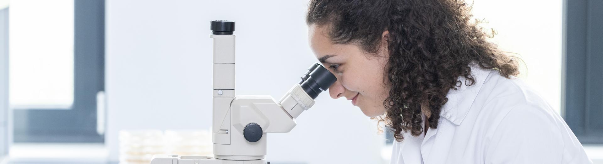 Junge Forscherin blickt durch Mikroskop