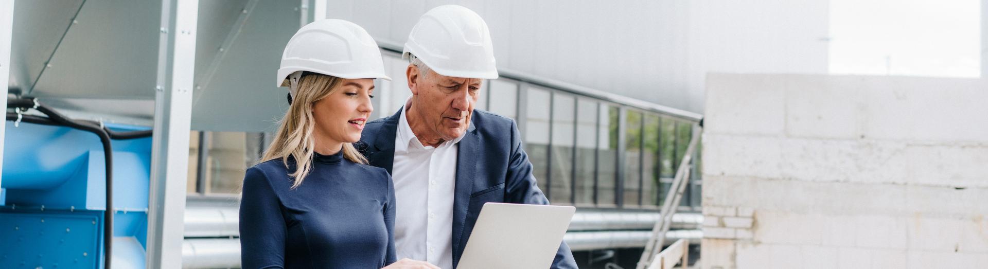 Zwei Kollegen der Baubranche werfen gemeinsam einen Blick auf den Laptop Bildschirm