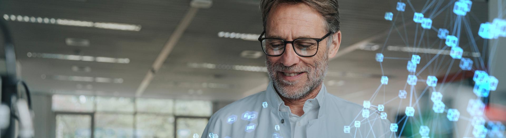 Mann mit weißem Forschungsmantel hält Ipad mit schwebenden Icons in Händen