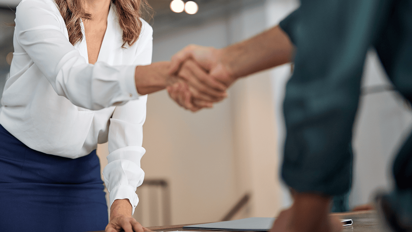 Junge Dame in Businesskleidung schüttelt Geschäftspartner die Hand