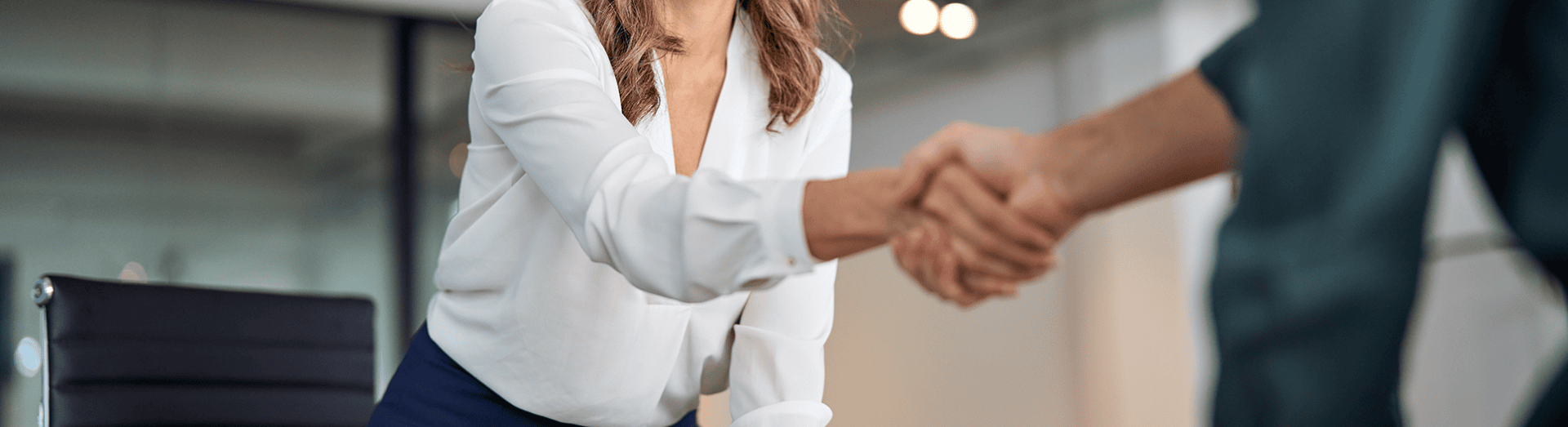Junge Dame in Businesskleidung schüttelt Geschäftspartner die Hand