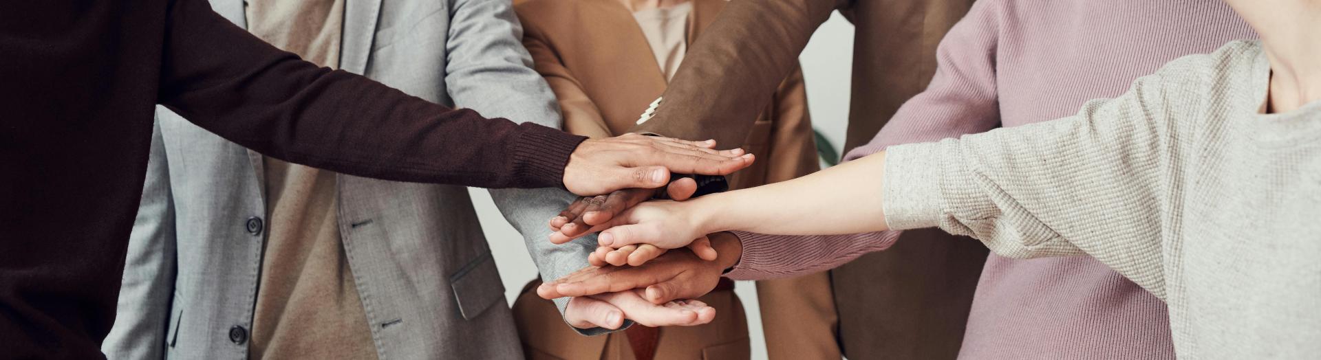 einige Leute stehen im Halbkreis und legen ihre Hände übereinander
