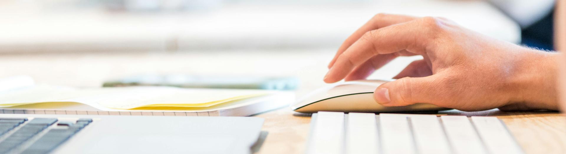 ein Laptop, eine Tastatur und eine Computermaus sind auf einem Tisch