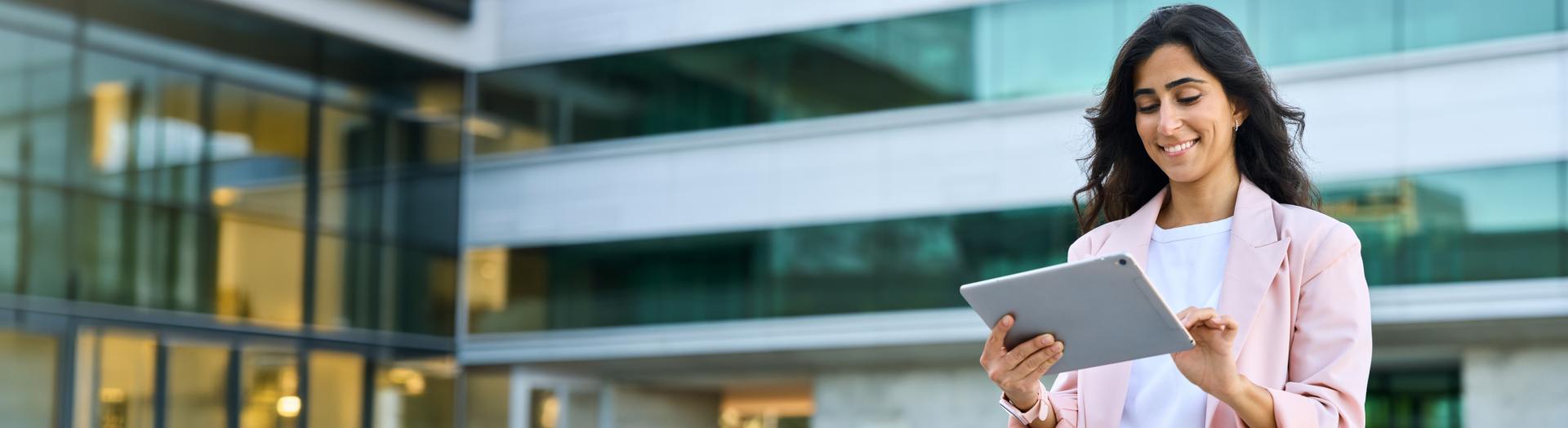 Internationale junge Businesslady mit tablet vor einem modernen Bürogebäude