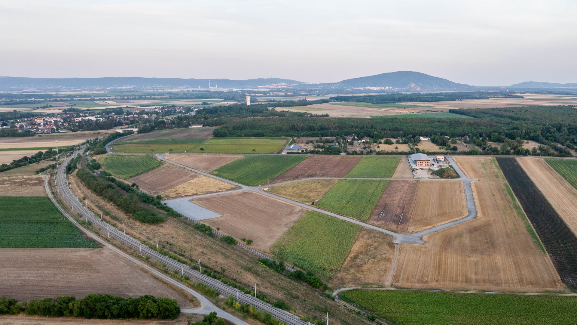 Drohnenfoto mit Bahnlinie, Ackerflächen und Straßenzügen sowie der Stadt Marchegg im Hintergrund