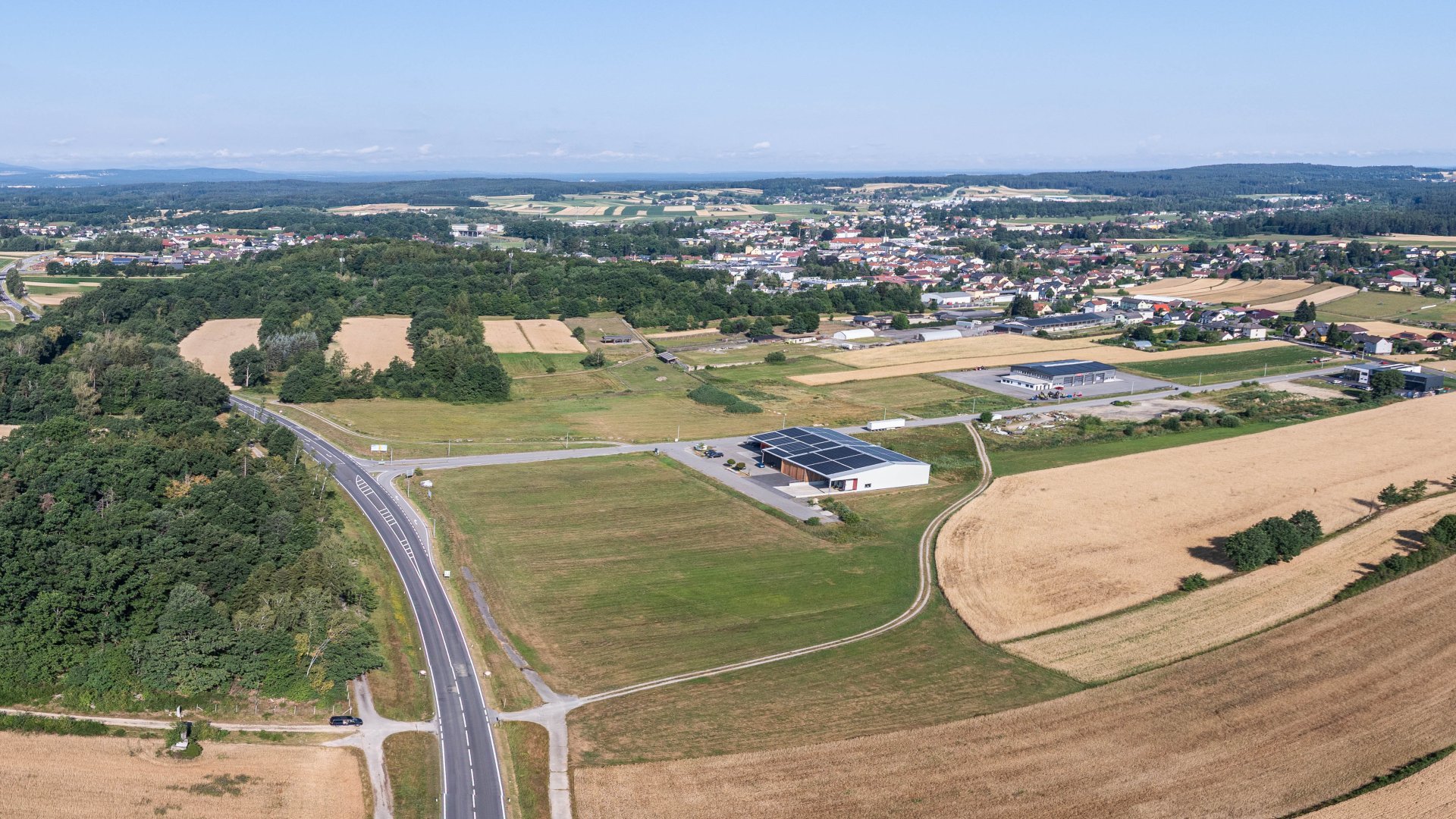 Drohnenaufnahme mit Panorama-Ansicht einer kleinen Stadt mit Unternehmen im Vodergrund