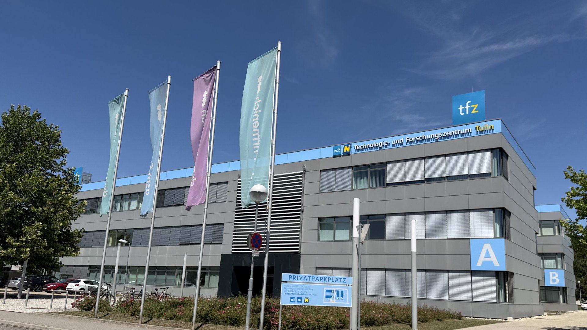 Außenaufnahme von TFZ Tulln mit Fahnen und Tafel Privatparkplatz