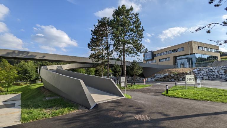 geschwungene Fußgänger/Fahrradbrücke zum xista science Gebäude am Hang