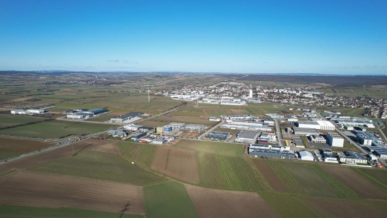 Drohnenansicht Wirtschaftspark Wolkersdorf umgeben von Feldern, der Stadt Wolkersdorf und Windrädern