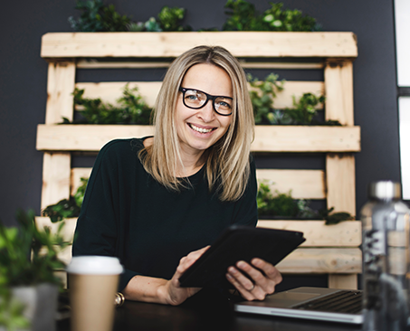 blonde Dame mit Brille mit Tablet in Händen