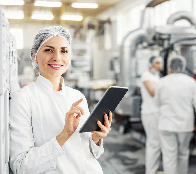Dame mit Ipad steht in einem lebensmittelverarbeitenden Betrieb