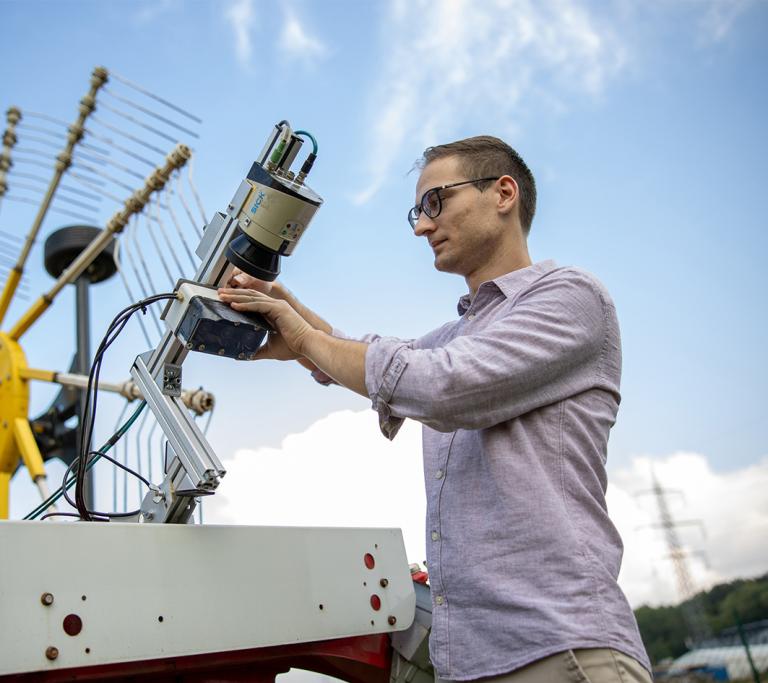 Mann arbeitet am Sensor einer landwirtschaftlicher Maschine
