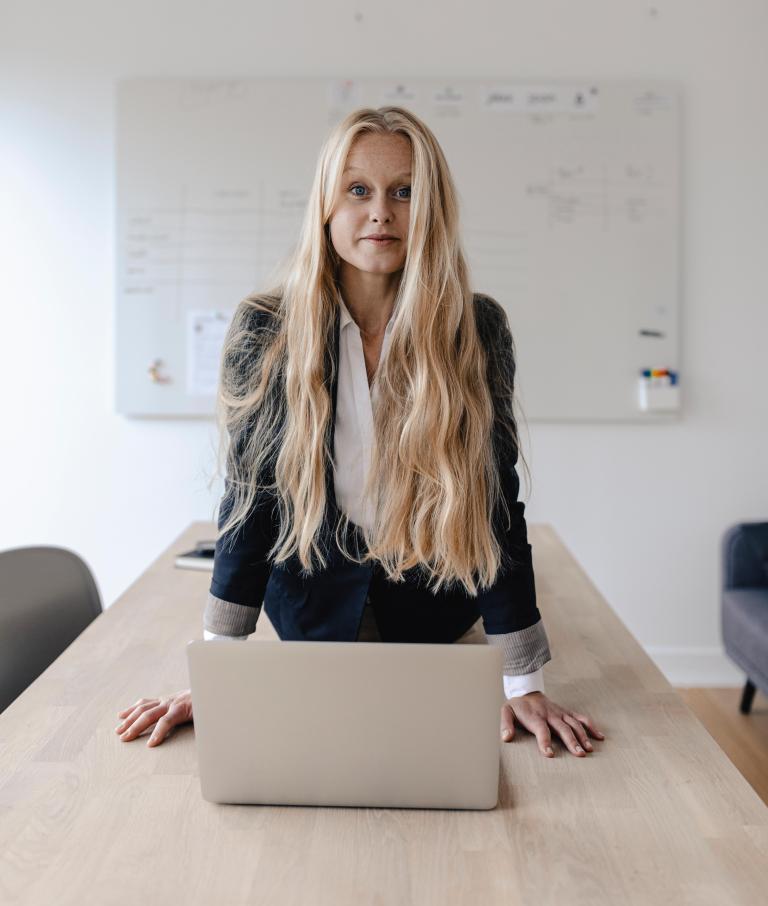 Businesslady im Anzug macht Cobra-Figur am Tisch