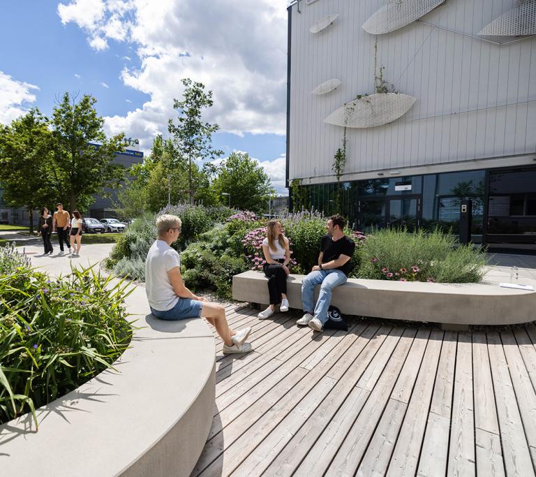 Studierende sitzen im Innenhof vom Haus der Digitalisierung