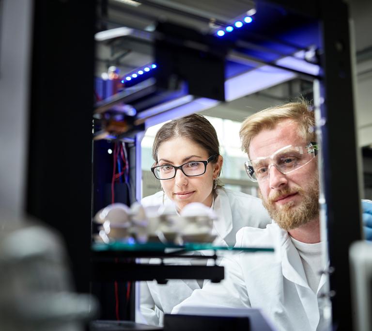 Dame und Herr sitzen vor Laserdrucker