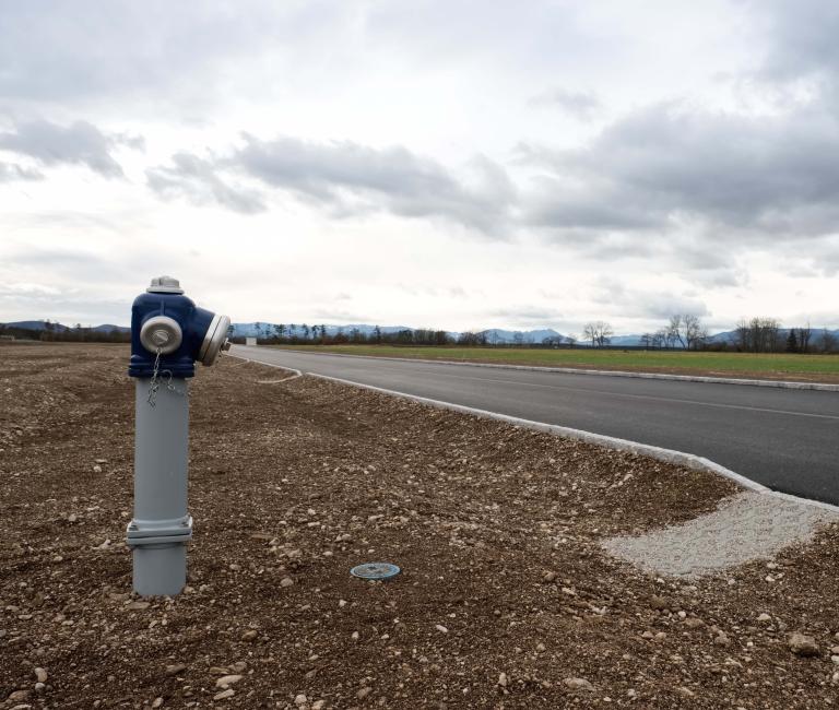 Asphaltierte Straße mit Hydranten und noch leeren Betriebsgründen
