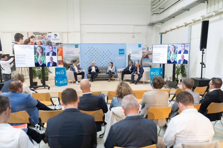 Zuschauer sitzend mit Blick auf Bühne, wo fünf Personen sitzen