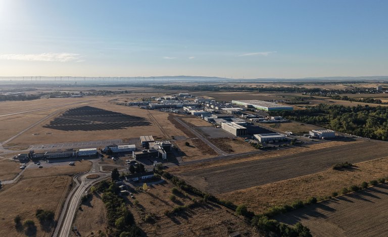 Drohnenaufnahme eines Wirtschaftspark Areals in einer Ebene mit Morgensonne