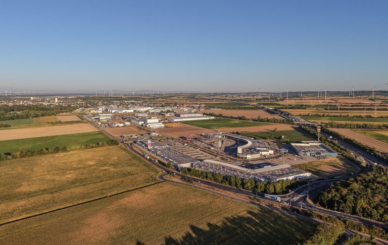 Fachmarktzentrum mit Straßen, Felder, Windrädern und einem Wirtschaftsparkareal am Rande einer Stadt