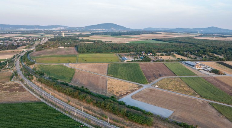 Drohnenaufnahme von Feldern, einzelnen Betriebsgebäuden und der Stadt Marchegg im Hintergrund