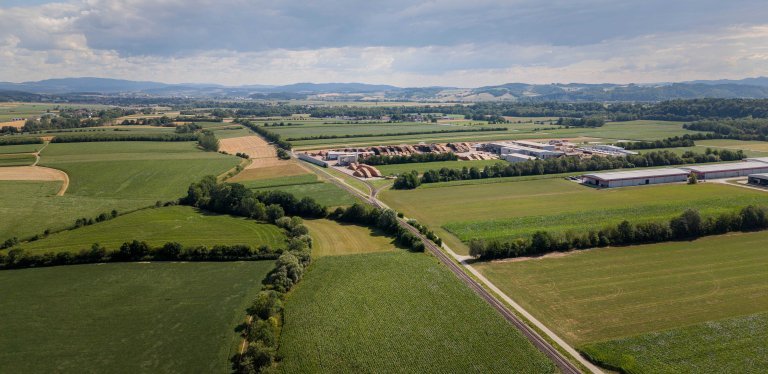 Drohnenaufnahme eines Wirtschaftspark Areals im Alpenvorland mit vielen grünen Feldern
