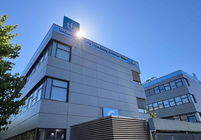 Sonne blinzelt über großen Gebäude mit TFZ Schriftzug