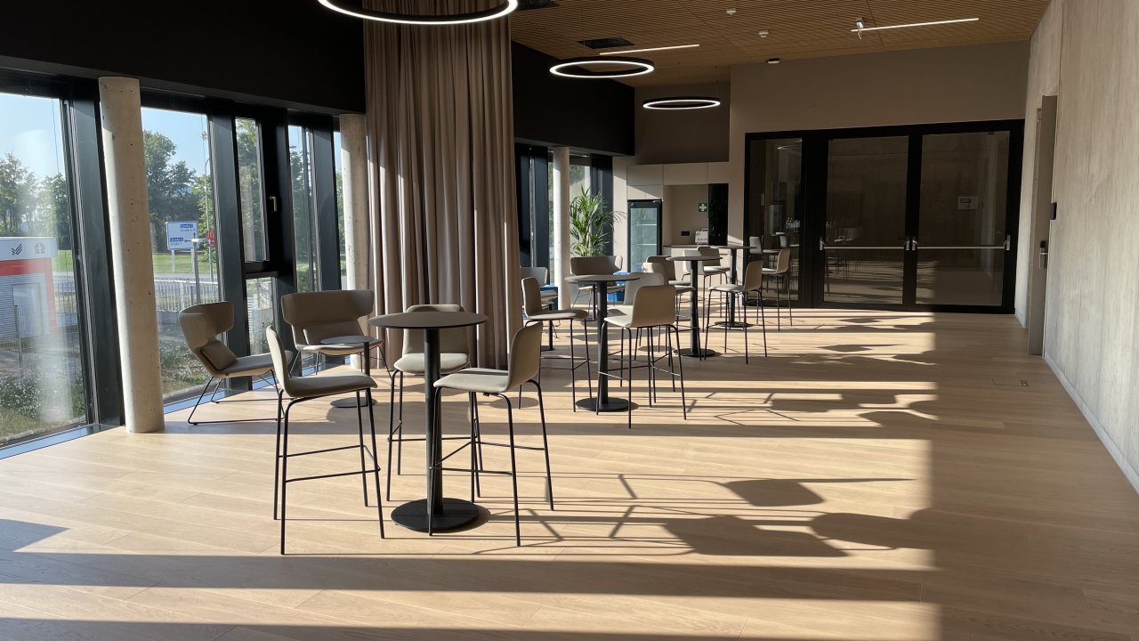 Seminarraum im Morgenlicht mit großen Fenstern und stielvollen Möbeln Tischgruppen