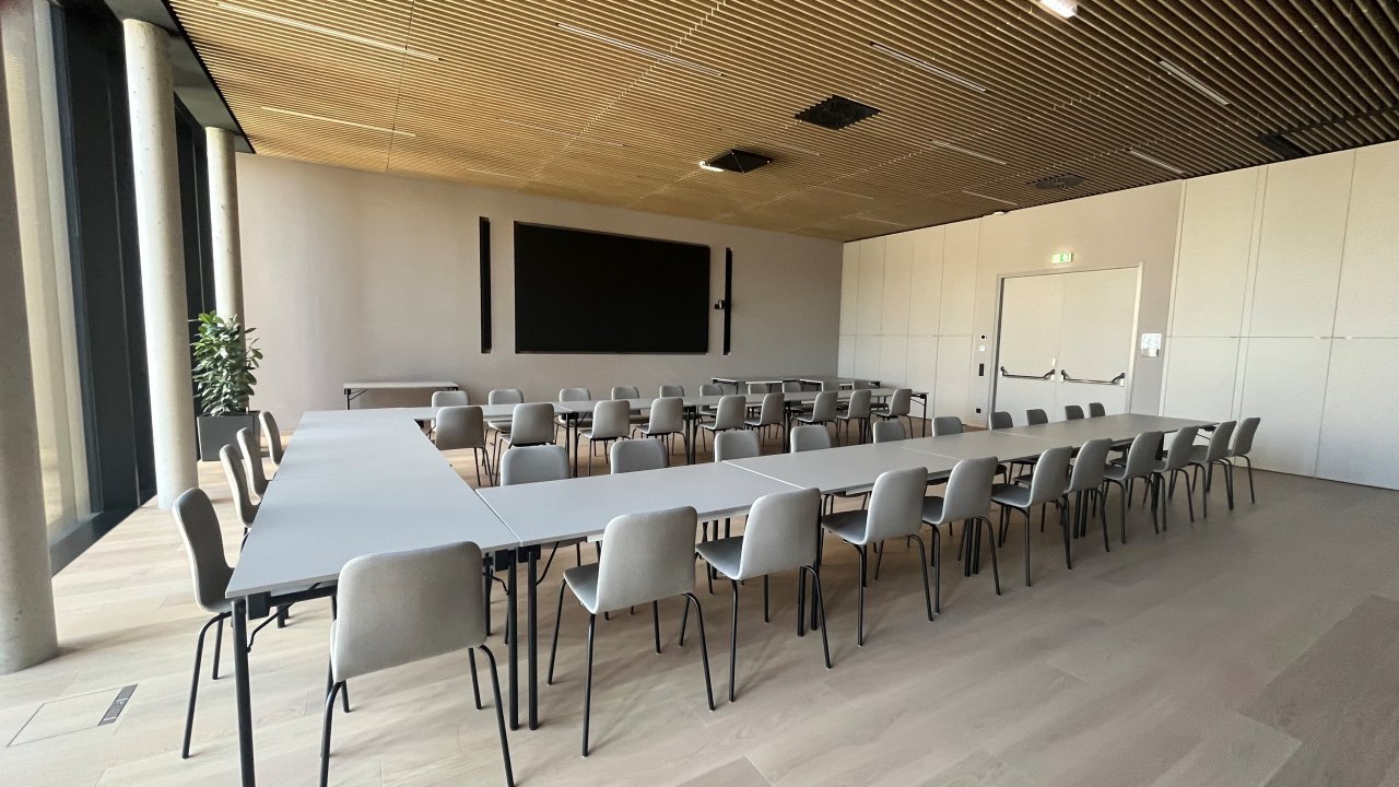Innenansicht eines bestuhlten modernen Seminarraums mit großem Display an der Wand