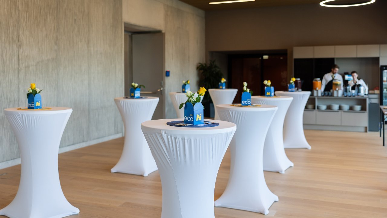 Eventlocation mit dekorierten Stehtischen und Getränkespendern