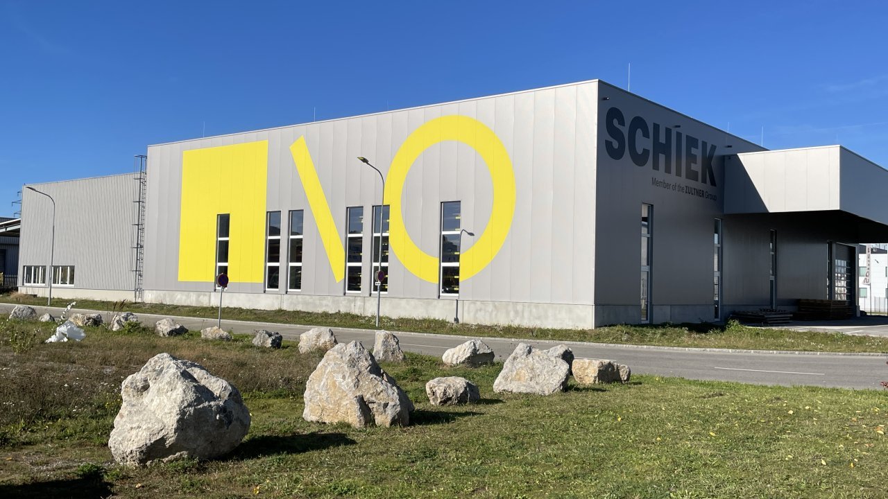 Außenansicht eines Bürogebäudes mit Firmenaufdruck und gelben Logo