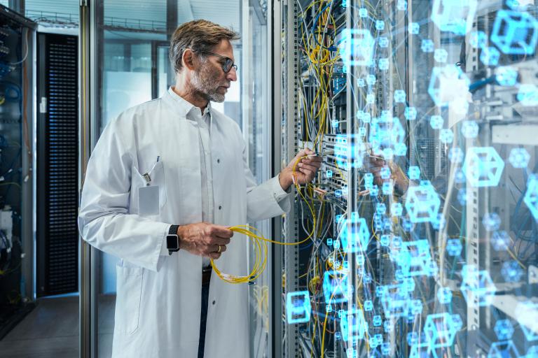 Älterer männlicher Techniker beim Einstecken von Glasfaserkabeln im Rechenzentrum