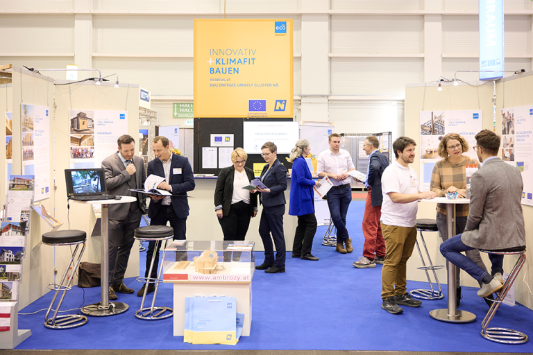 mehrere Personen stehen auf einem Messestand und unterhalten sich in Kleingruppen
