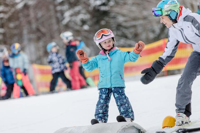 Kind auf Ski mit Mutter in einem Kinderskiland