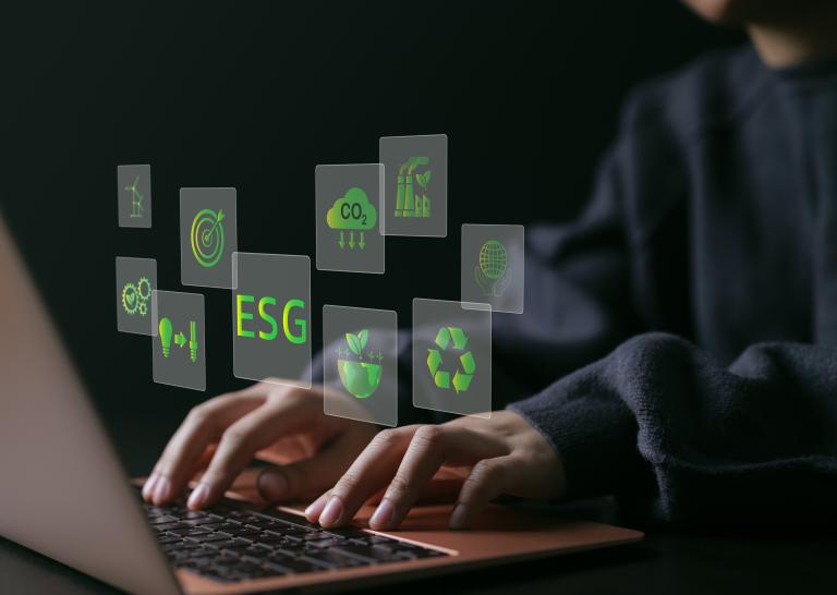 schreibende Finger auf Laptop zu sehen mit Icons rund um das Thema ESG