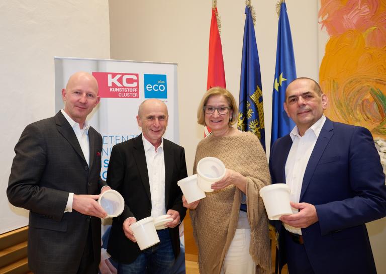 vier Personen stehen nebeneinander und lachen in die Kamera