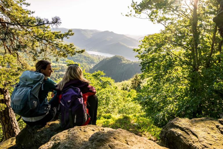 Zwei Frauen sitzen auf Granitfelsen auf Hügeln mit Blick zum Donauflussrhalb der Donau