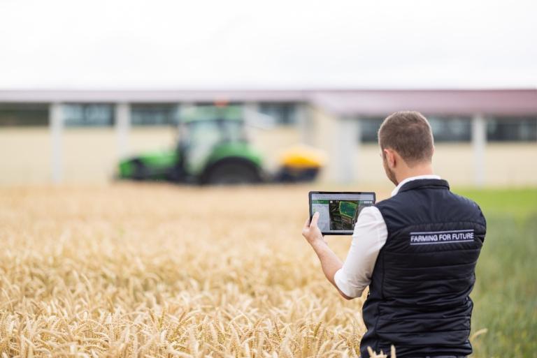 Mann steht mit IPad am Feld