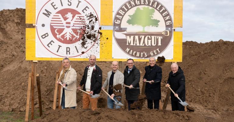 Sechs Personen mit Schaufeln beim Spatenstich der Baustelle
