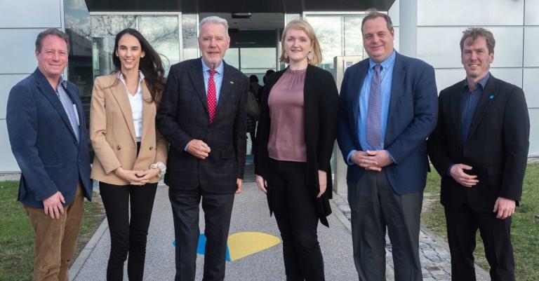 Sechs Personen stehen nebeneinander vor Gebäudeeingang