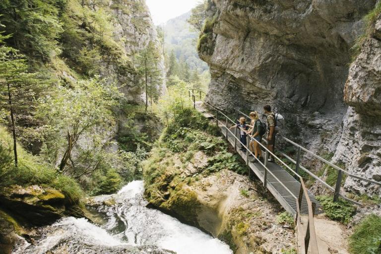 Drei Personen stehen an einem gesicherten Wanderpfad in einer Klamm.