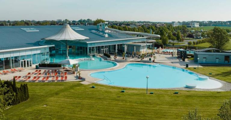 Ein Gebäudekomplex mit einem Pool im Vordergrund und einer grünen Wiese 