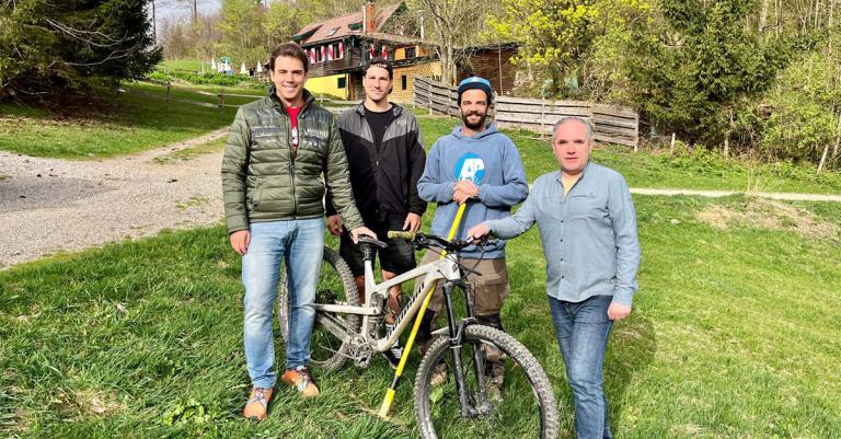 4 Herren stehen mit MTB auf einer Wiese vor einer Berghütte