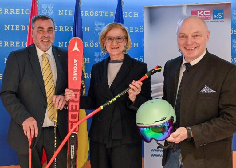 drei Personen stehen in einer Reihe und halten einen Ski