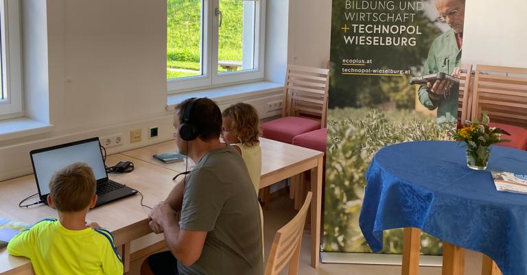 Mann sitzt mit zwei Kindern vor einem Laptop