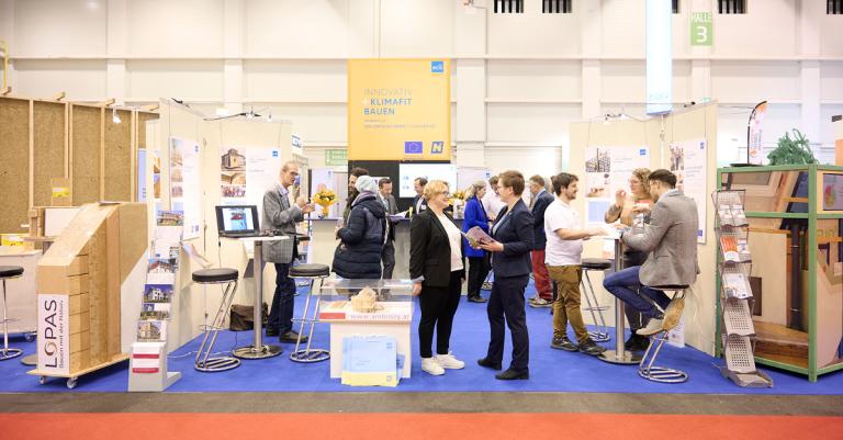 Schnappschuss auf der Messe in Wieselburg vom Bau.Energie.Umwelt Cluster Stand und sich unterhaltenden Personen