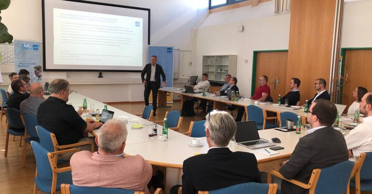 Viele Personen sitzen gemeinsam in einem Vortragsraum